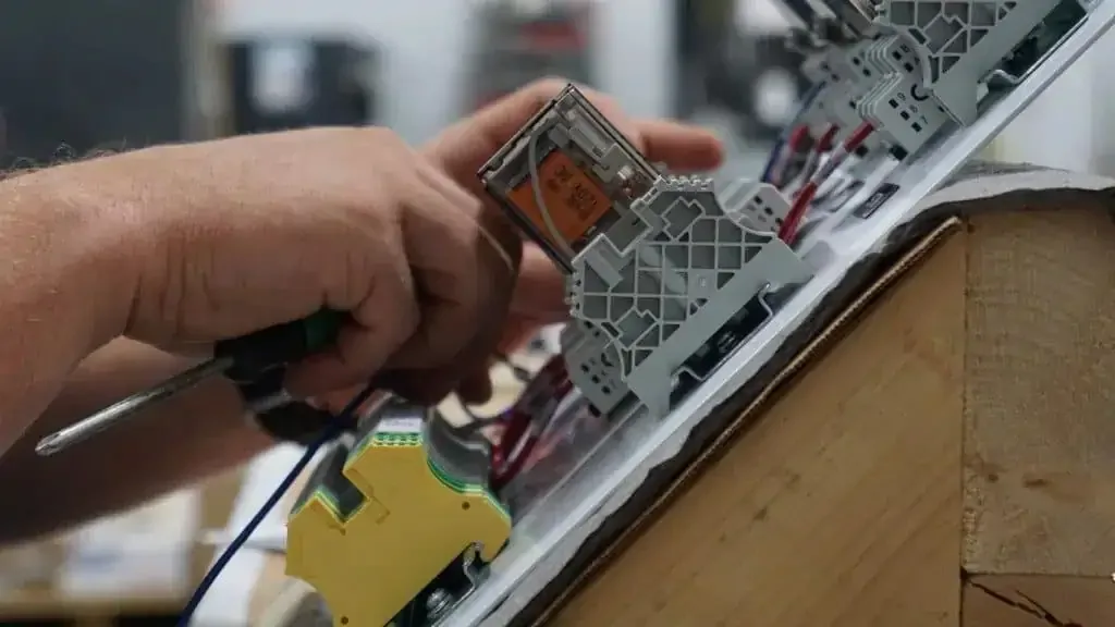 Close-up of a technician wiring terminal blocks in a control panel